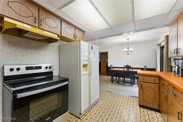 kitchen featuring decorative light fixtures, a notable chandelier, stainless steel electric range oven, white fridge with ice dispenser, and a paneled ceiling