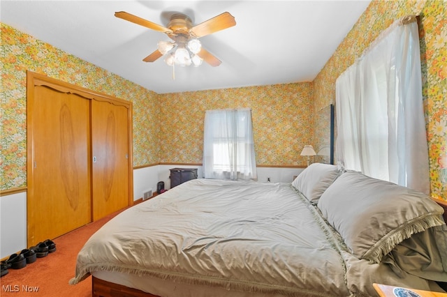 bedroom with light colored carpet, ceiling fan, and a closet