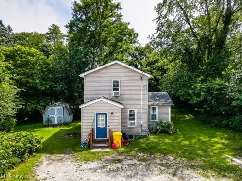 back of property with a lawn and a storage shed