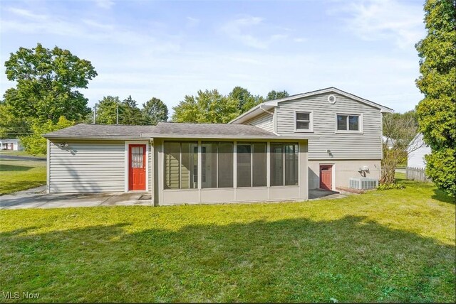 rear view of property with cooling unit, a yard, and a sunroom