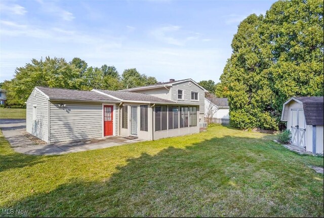 back of property with a yard, a storage unit, and a sunroom