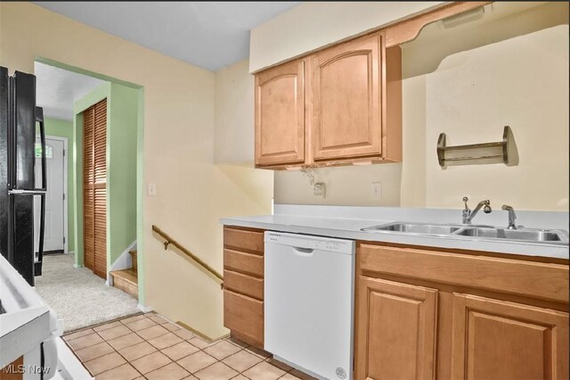 kitchen with black refrigerator, light brown cabinetry, white dishwasher, sink, and light tile patterned flooring