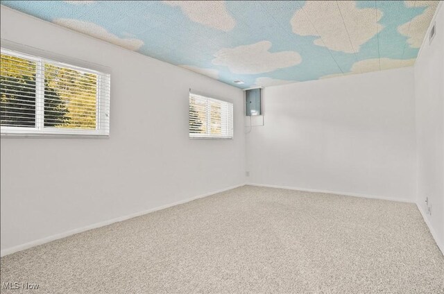 empty room with electric panel, a textured ceiling, and carpet floors