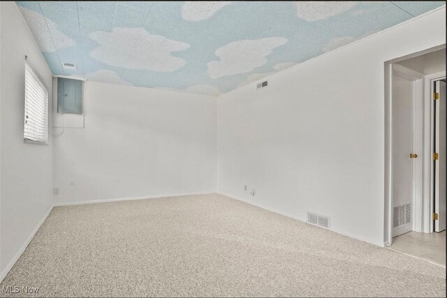 spare room featuring a textured ceiling, electric panel, and light colored carpet