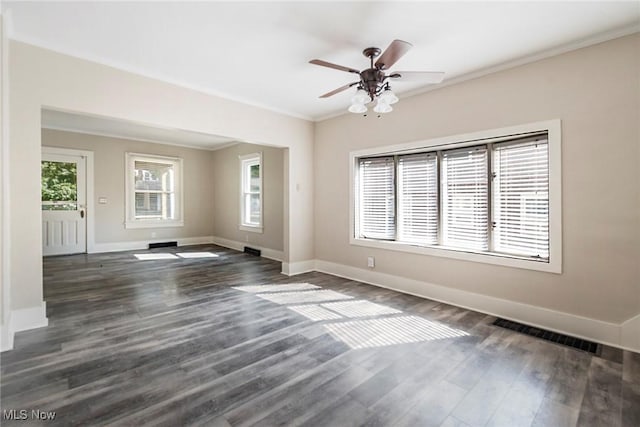 empty room with visible vents, baseboards, ornamental molding, a ceiling fan, and dark wood finished floors