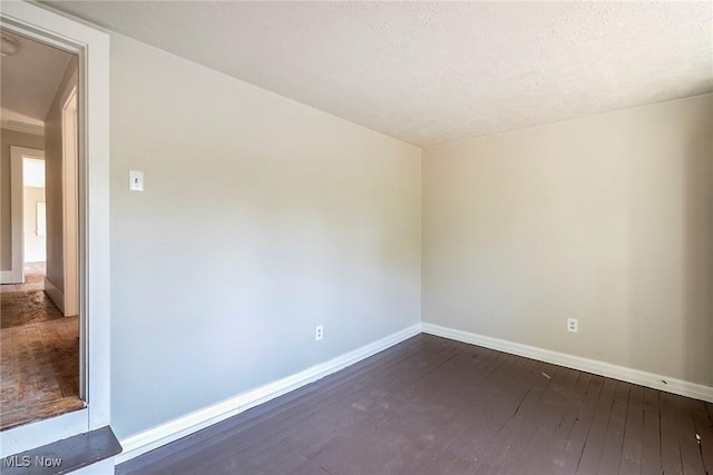 empty room with baseboards, dark wood-style flooring, and a textured ceiling