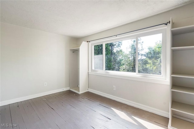 empty room featuring hardwood / wood-style floors, baseboards, and a textured ceiling
