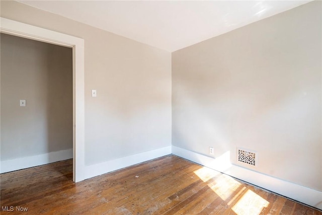 empty room featuring baseboards, visible vents, and wood-type flooring