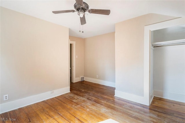 unfurnished bedroom with a closet, a ceiling fan, wood finished floors, baseboards, and visible vents