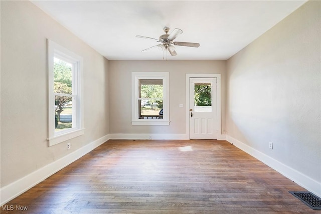 spare room with baseboards, ceiling fan, visible vents, and wood finished floors