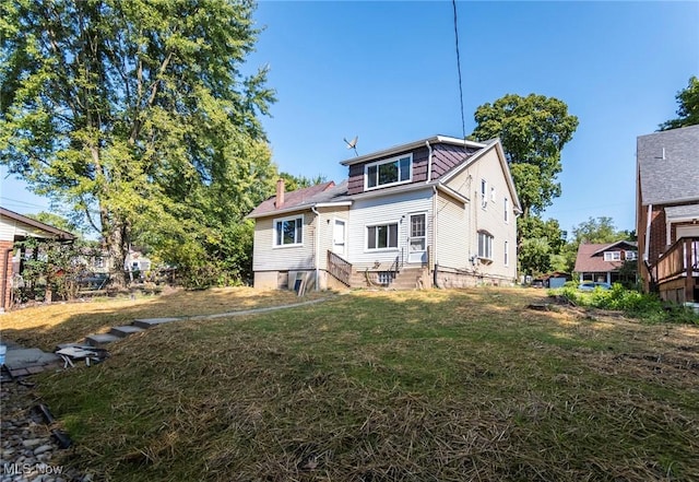 rear view of house with a lawn, a chimney, and entry steps