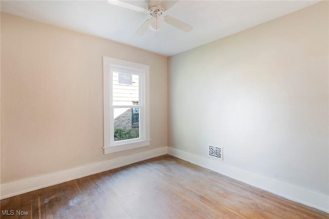 unfurnished room featuring baseboards, visible vents, wood finished floors, and a ceiling fan