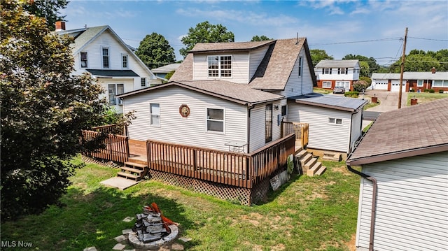 rear view of property with a fire pit, a wooden deck, and a yard