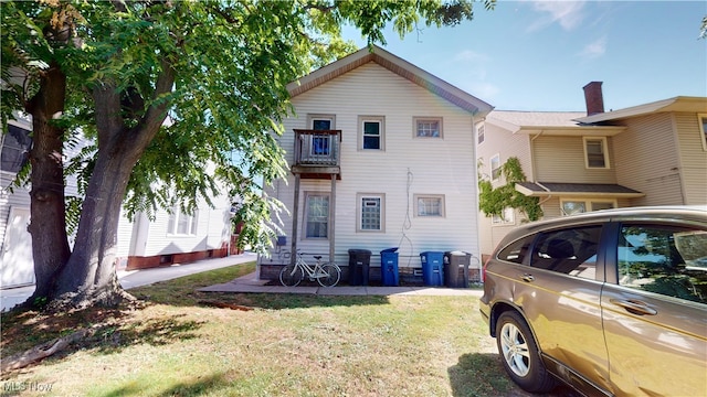 view of side of property featuring a yard and a balcony