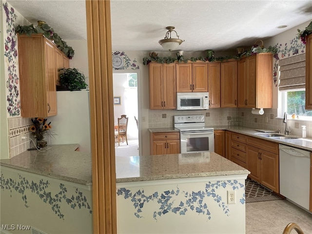 kitchen with white appliances, decorative backsplash, light tile patterned flooring, and sink