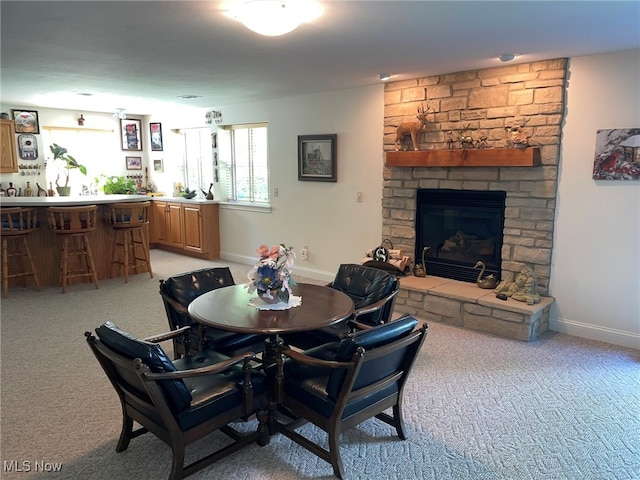 dining area with light colored carpet, indoor bar, and a stone fireplace