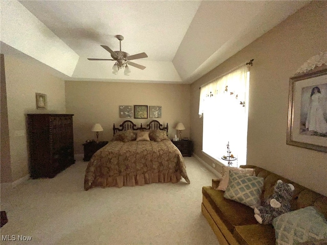 carpeted bedroom with a raised ceiling and ceiling fan