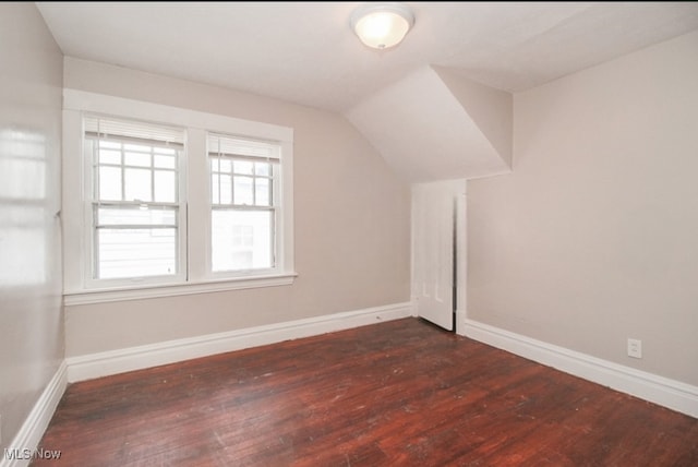 additional living space with dark hardwood / wood-style floors and vaulted ceiling