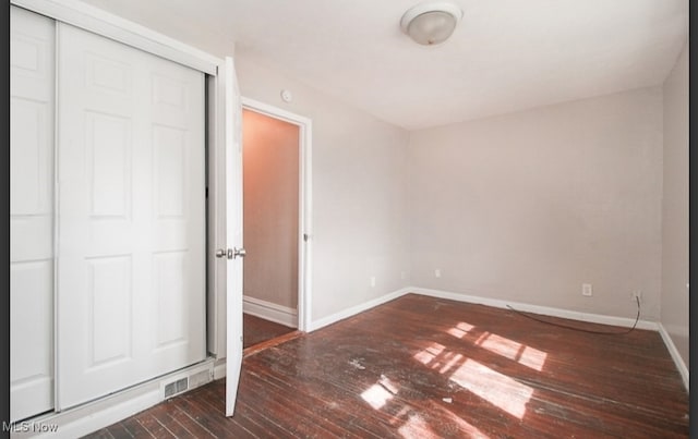 unfurnished bedroom featuring dark wood-type flooring and a closet