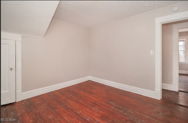 additional living space featuring a textured ceiling and dark hardwood / wood-style floors