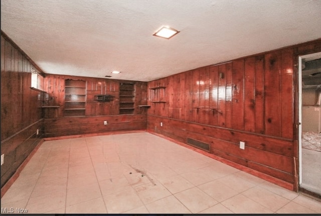 spare room with a textured ceiling and wood walls