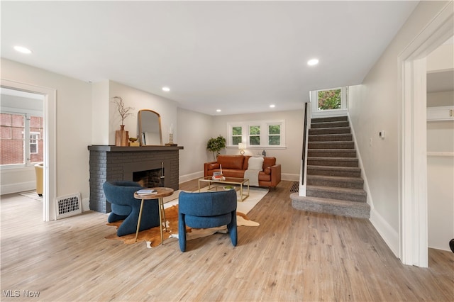 living room with a fireplace and light wood-type flooring