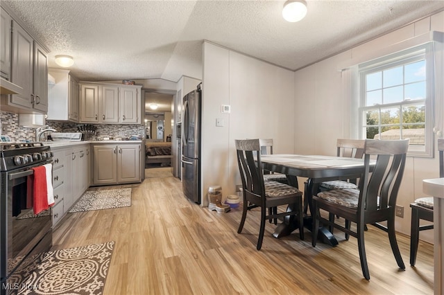 dining area with lofted ceiling, light hardwood / wood-style floors, and a textured ceiling