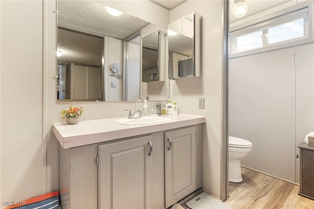 bathroom featuring toilet, hardwood / wood-style flooring, a textured ceiling, and vanity