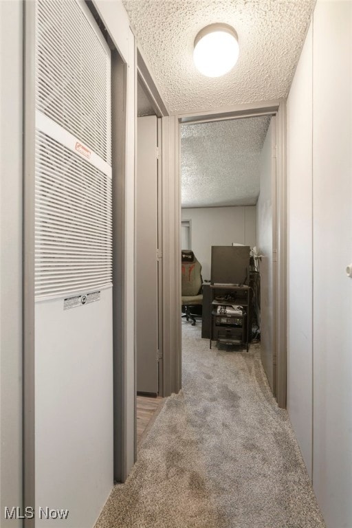 hall featuring a textured ceiling and light colored carpet