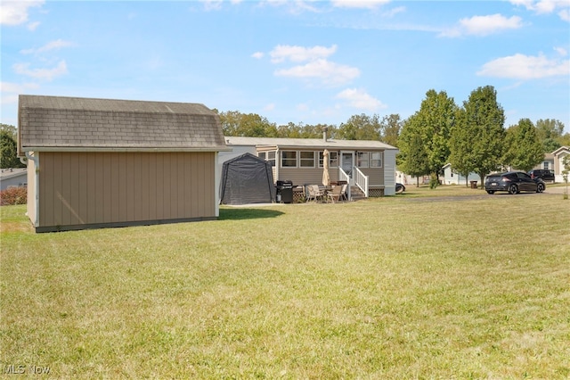 rear view of property with a yard and a shed