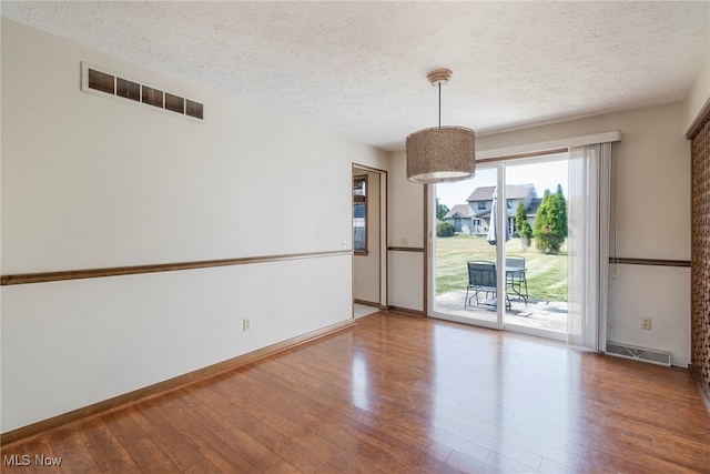 spare room featuring a textured ceiling and hardwood / wood-style flooring