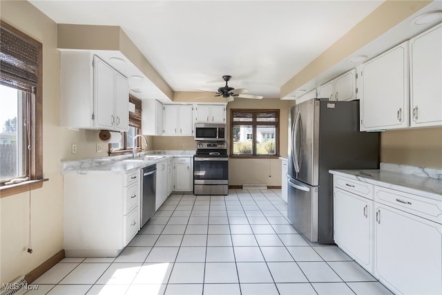 kitchen featuring light tile patterned floors, appliances with stainless steel finishes, sink, white cabinetry, and ceiling fan