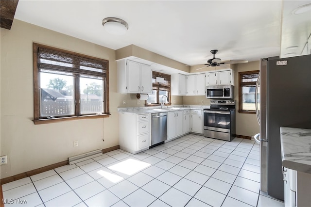 kitchen with white cabinets, light tile patterned floors, stainless steel appliances, sink, and ceiling fan