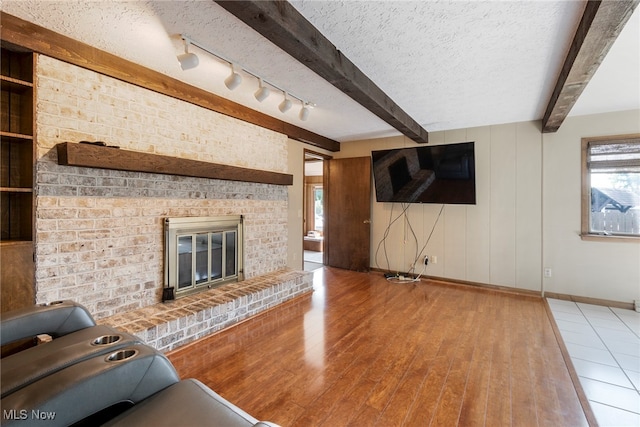 unfurnished living room with a textured ceiling, a brick fireplace, and hardwood / wood-style flooring