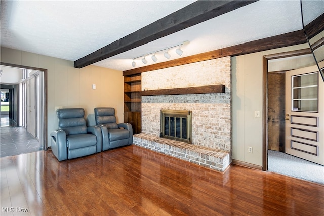 living room featuring a fireplace, beamed ceiling, hardwood / wood-style floors, and a textured ceiling