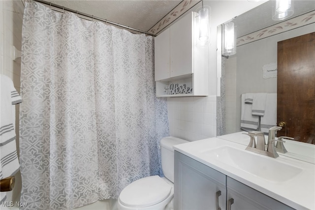 bathroom featuring toilet, tile walls, a shower with curtain, vanity, and a textured ceiling