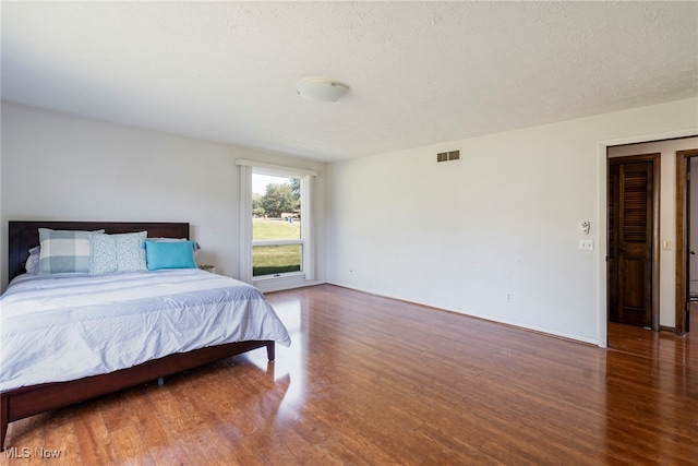 bedroom featuring dark hardwood / wood-style flooring and a textured ceiling