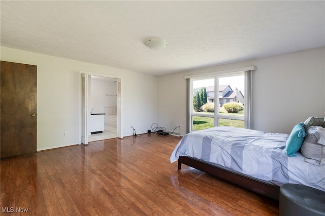 bedroom featuring a textured ceiling, wood-type flooring, and ensuite bathroom