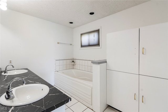 bathroom featuring a textured ceiling, vanity, a bathtub, and tile patterned flooring