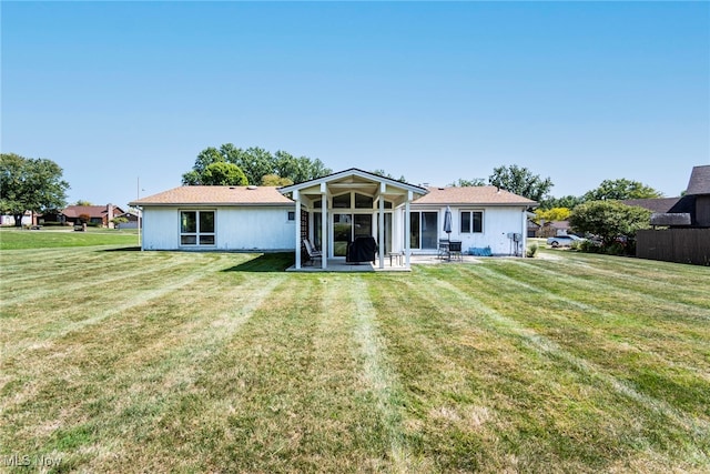 back of house featuring a lawn and a sunroom