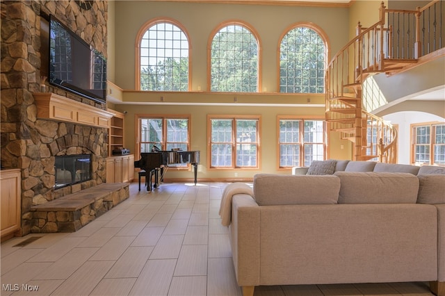 living room with a fireplace, a towering ceiling, and light hardwood / wood-style flooring