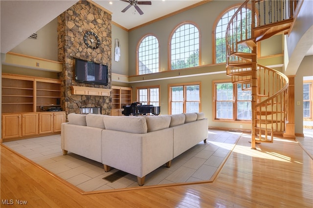 living room featuring a fireplace, light hardwood / wood-style floors, crown molding, high vaulted ceiling, and ceiling fan