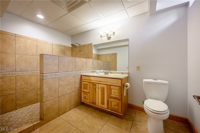 bathroom featuring toilet, tile patterned floors, vanity, a paneled ceiling, and a shower