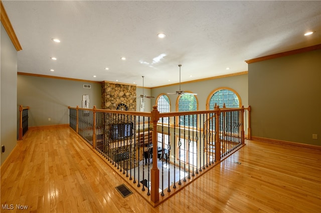 corridor featuring ornamental molding, a textured ceiling, and light hardwood / wood-style flooring