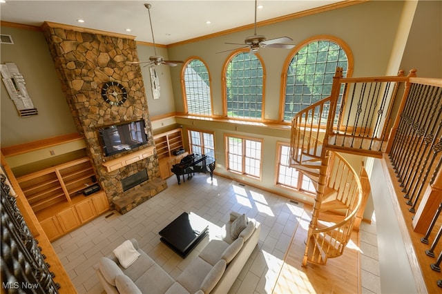 living room with ceiling fan, ornamental molding, light wood-type flooring, and a fireplace