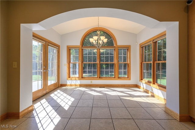 doorway featuring lofted ceiling, a wealth of natural light, light tile patterned flooring, and a notable chandelier