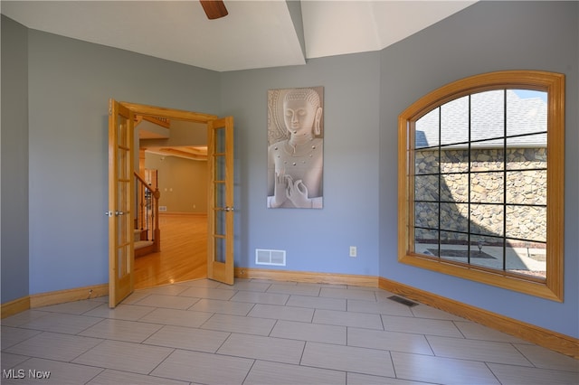 empty room with french doors, ceiling fan, and light hardwood / wood-style flooring