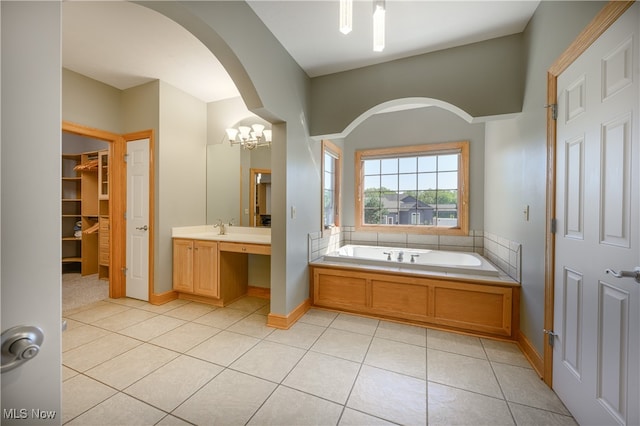 bathroom with tile patterned flooring, a tub to relax in, a chandelier, and vanity