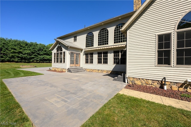 rear view of property featuring a lawn and a patio area