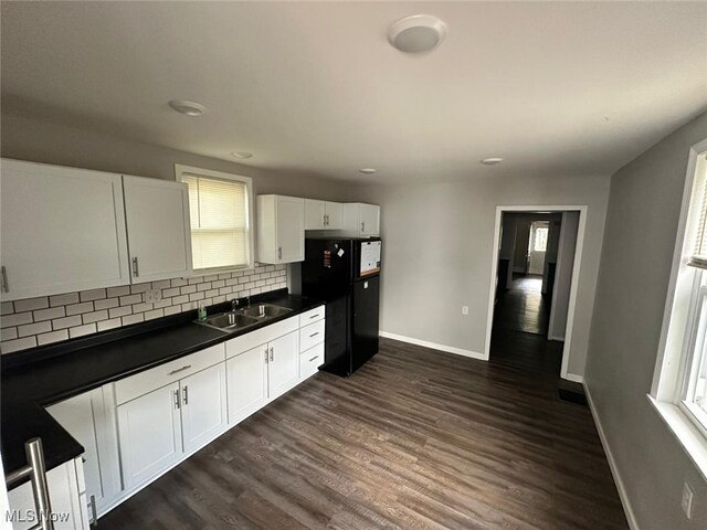 kitchen featuring white cabinetry, sink, black refrigerator, dark hardwood / wood-style floors, and decorative backsplash